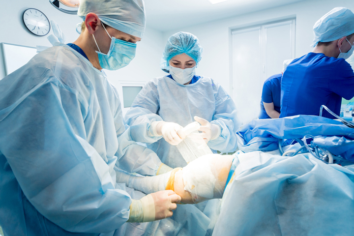 Surgeons wrap a knee following knee cartilage repair surgery.